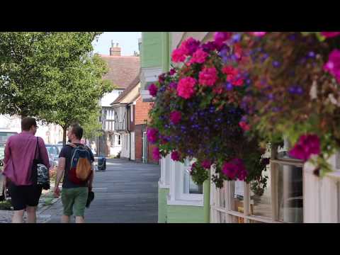 Tourists walking in Faversham, next to flowers on a shop.